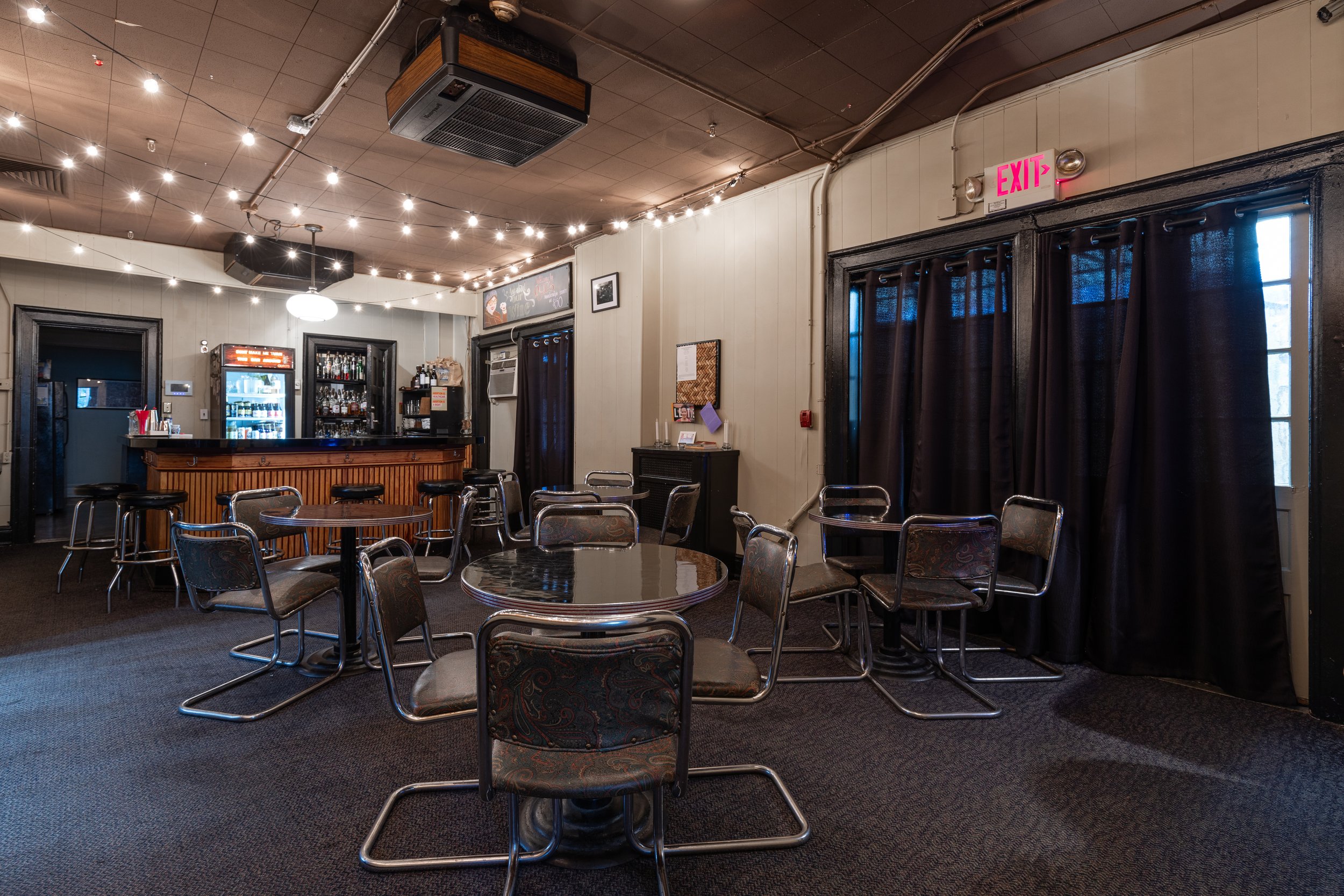 Quig's Pub with bistro tables, string lights, and the bar
